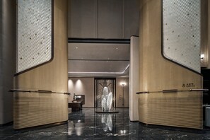 Un hall d’entrée agrémenté d’une sculpture centrale, d’un comptoir de réception et d’un sol en marbre poli.