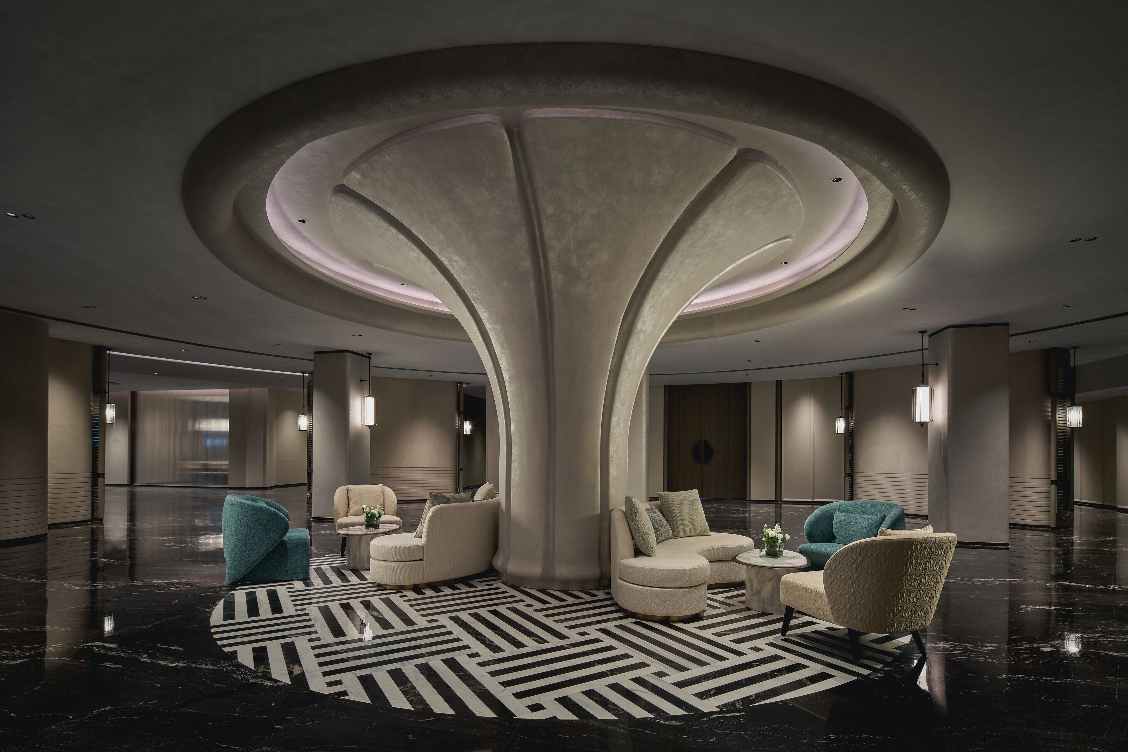 A modern lobby with a central column, seating area, and a patterned floor.