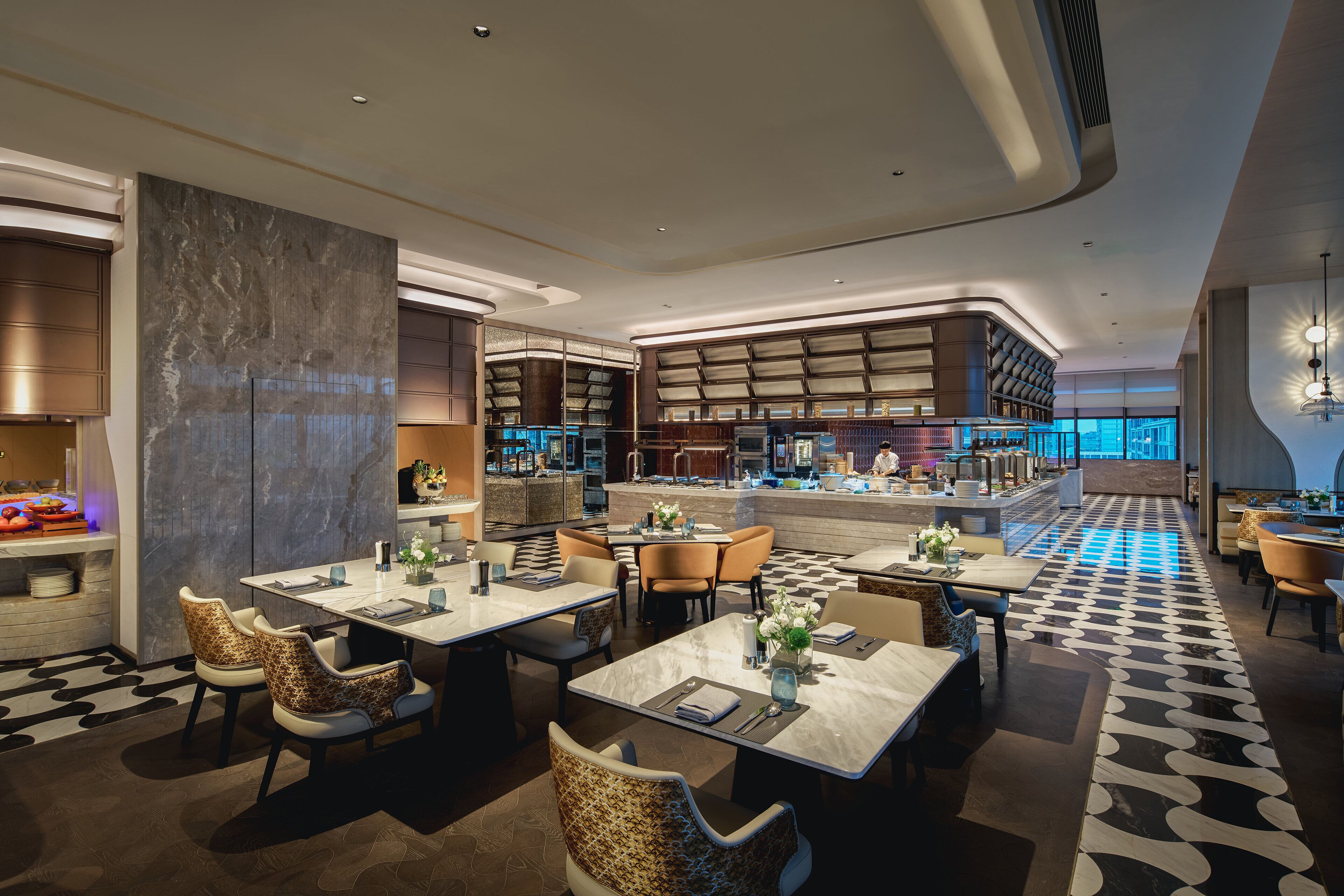 A modern restaurant with marble tables and chairs, a patterned floor, and a bar area with a view.