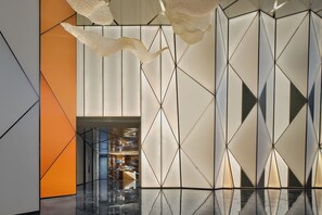 A modern interior with geometric wall patterns, a reflective floor, and a central corridor leading to a seating area. - Hotel Indigo Shanghai Harbour City by IHG (Shanghai)