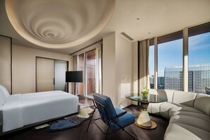A modern hotel room with a bed, a sofa, a chair, a small table, and a large window offering a city view. - Hotel Indigo Shanghai Harbour City by IHG (Shanghai)