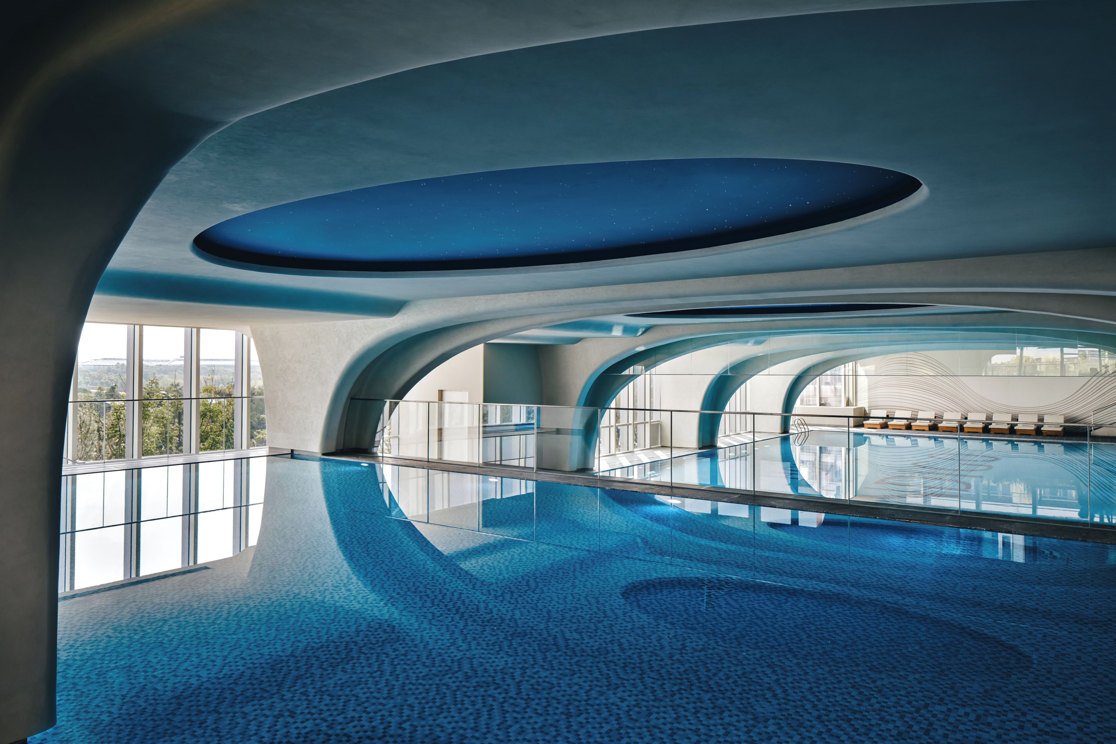Una piscina interior con diseño moderno, ventanas amplias y vistas a la ciudad.