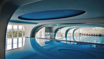 Una piscina interior con diseño moderno, ventanas amplias y vistas a la ciudad.