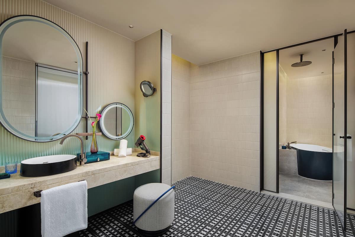 A modern bathroom with a round mirror, a sink, a toilet, and a shower.