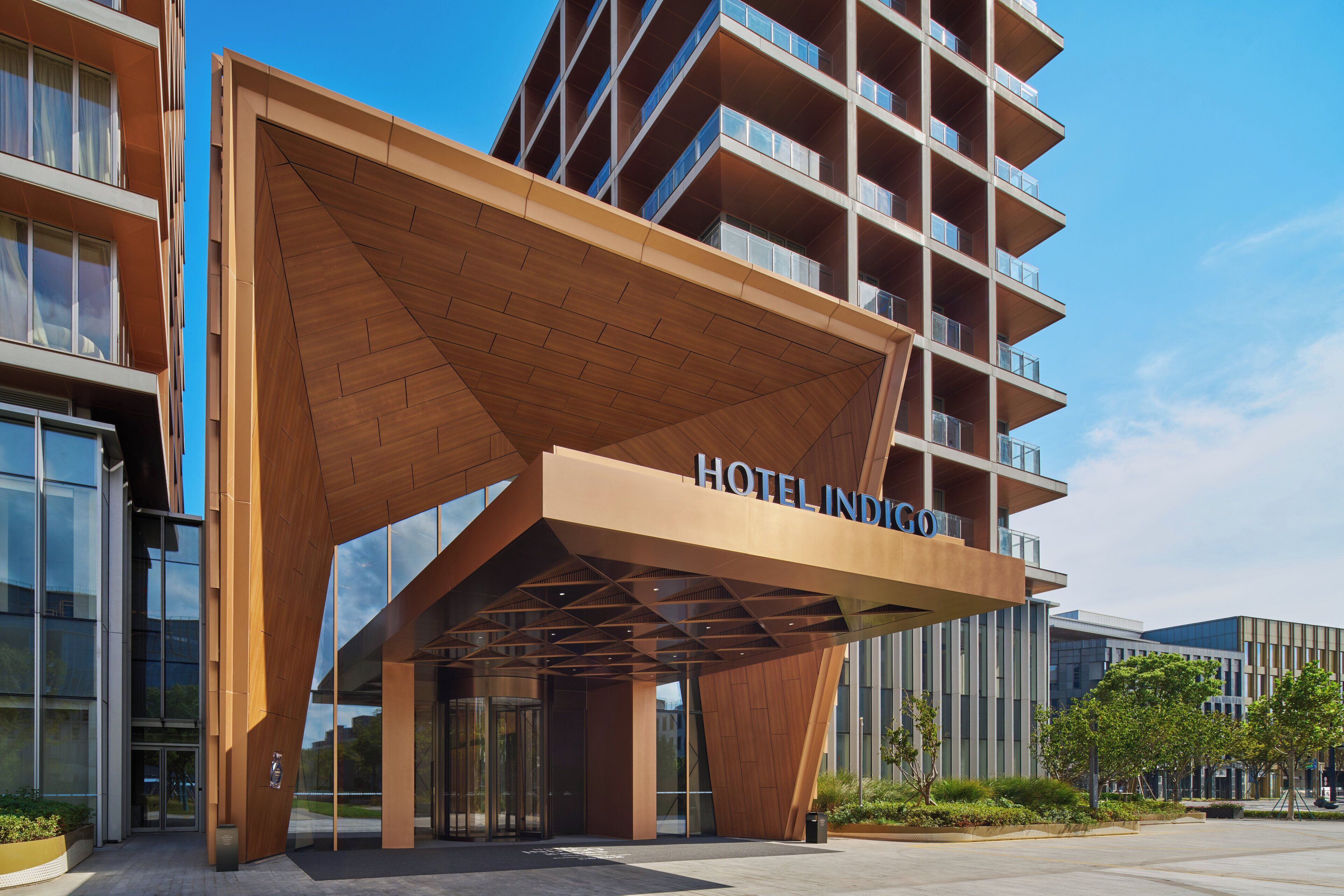 A modern hotel with a prominent wooden entrance canopy and multiple balconies.