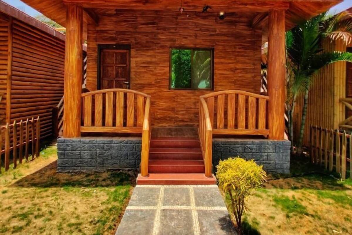 A wooden house with a porch, stone steps, and a small garden.