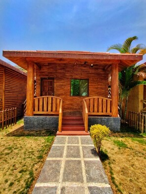 A wooden house with a porch, stone steps, and a small garden. - Malshej Agro Tourism & Farm (Junnar)