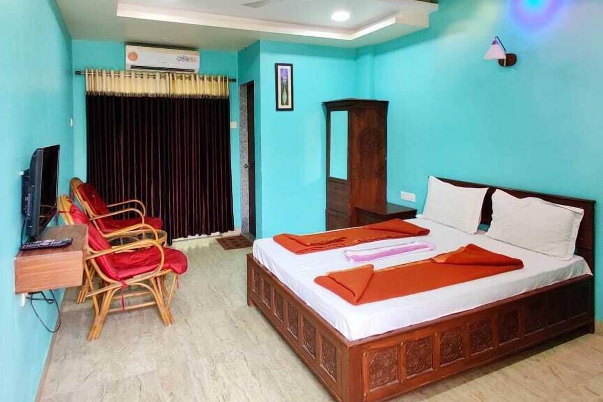 A bedroom with a bed, a desk with a chair, a ceiling fan, and an air conditioning unit.