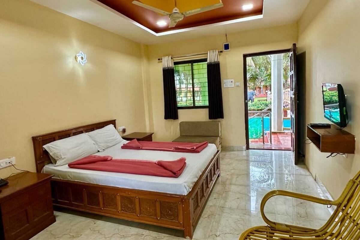 A hotel room with a bed, a wooden nightstand, a television, and a chair.