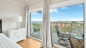 Ein Schlafzimmer mit großem Balkon, einem weißen Schminktisch und Blick auf die Stadt.