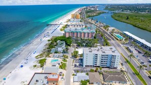 Ein Küstenhotel mit direktem Strandzugang, mehreren Schwimmbecken und einer Straße, die parallel zum Strand verläuft.