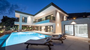 A modern two-story house with a swimming pool, outdoor seating, and large windows. - Beachfront Villa Nautilux with Pool (Seget Donji)