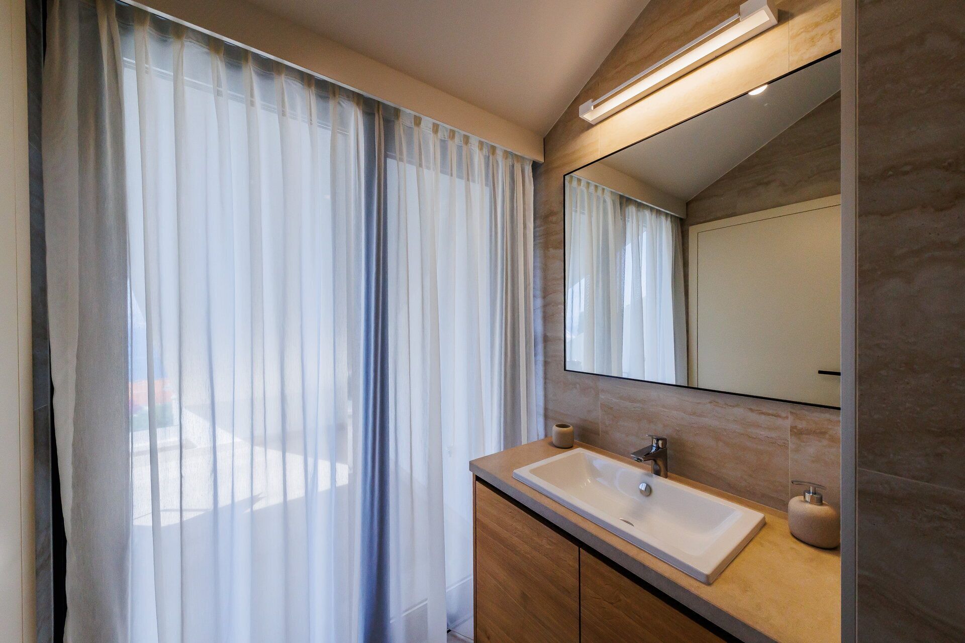 Une salle de bain moderne avec une grande fenêtre, un lavabo et un miroir.