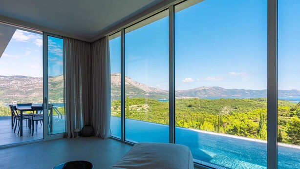 Un dormitorio con un ventanal grande que da a un paisaje pintoresco, una cama y una mesa con sillas.