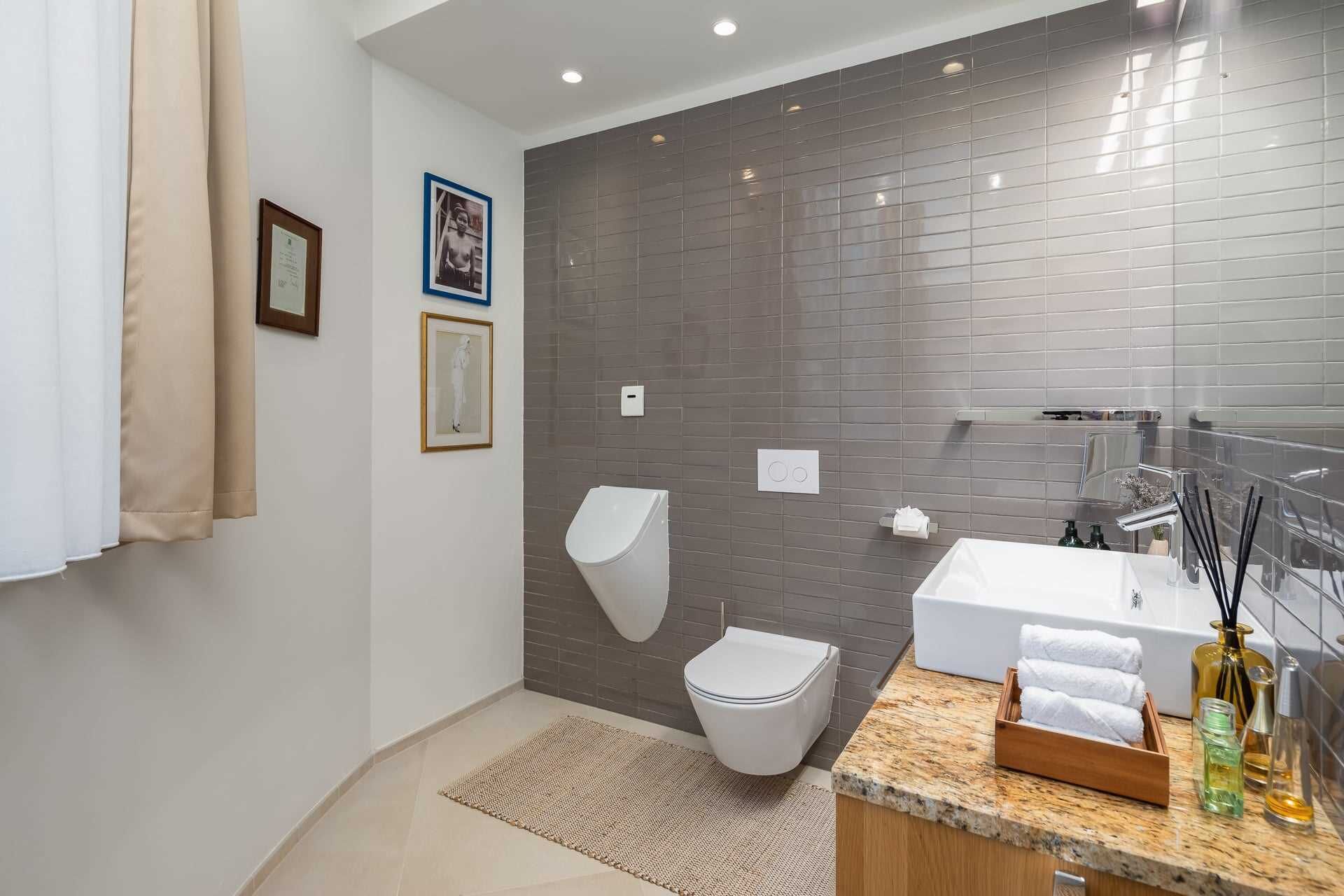 Un bagno moderno con il water bianco, un lavabo ampio con specchio e una zona doccia.