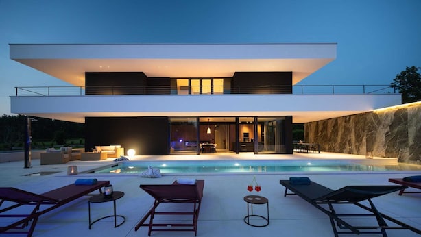 A modern two-story house with a swimming pool, outdoor seating, and a large glass door leading to the interior. - Luxury Villa Sylva with Pool (Grožnjan)