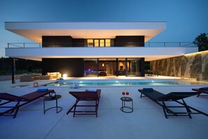 A modern two-story house with a swimming pool, outdoor seating, and a large glass door leading to the interior. - Luxury Villa Sylva with Pool (Grožnjan)