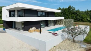 A modern two-story house with a large balcony, a swimming pool, and outdoor seating. - Luxury Villa Sylva with Pool (Grožnjan)