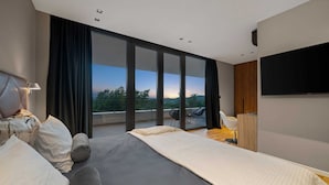 A modern hotel room with a large bed, a flat-screen TV, and a balcony with a scenic view. - Luxury Villa Sylva with Pool (Grožnjan)