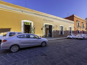 Un hotel llamado 'HOTEL POSADA' con una calle pavimentada en su fachada.