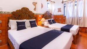 A hotel room with two beds, a wooden headboard, a lamp, and a window with curtains.