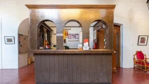 A reception desk with a wooden finish, arched doorways, and a red chair to the side.