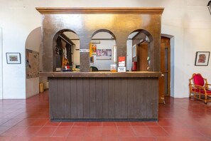 Un mostrador de recepción con detalles de madera, arcos y una silla roja a un lado.