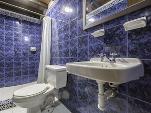 Un baño con inodoro y lavamanos blancos, y una cortina de ducha.