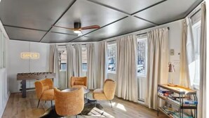A room with a foosball table, four orange chairs, a ceiling fan, and a bookshelf. - sleeps six, close to slopes, hot tub and game room private hot tub (Albrightsville)