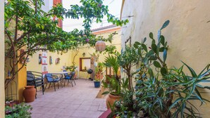 Un espace extérieur aménagé en terrasse, avec un sol carrelé, des plantes en pot et du mobilier d’extérieur.