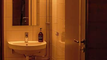 Un baño con un lavamanos blanco, un espejo y una ducha.