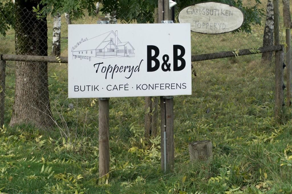 A sign for Topperyd B&B with a barn illustration, indicating it offers a bed, café, and conference facilities.