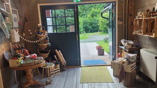 Un intérieur rustique avec des planchers en bois, une grande fenêtre et une porte donnant sur l’extérieur.