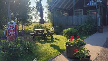 A wooden building with a porch, a picnic table, and potted plants.