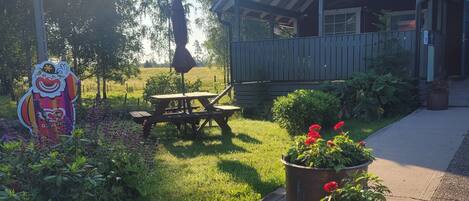 Ein hölzernes Gebäude mit Veranda, Picknicktisch und Blumentöpfen.