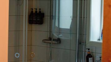 Eine Dusche mit Glastür, einer Handbrause und einer Seifenspender.