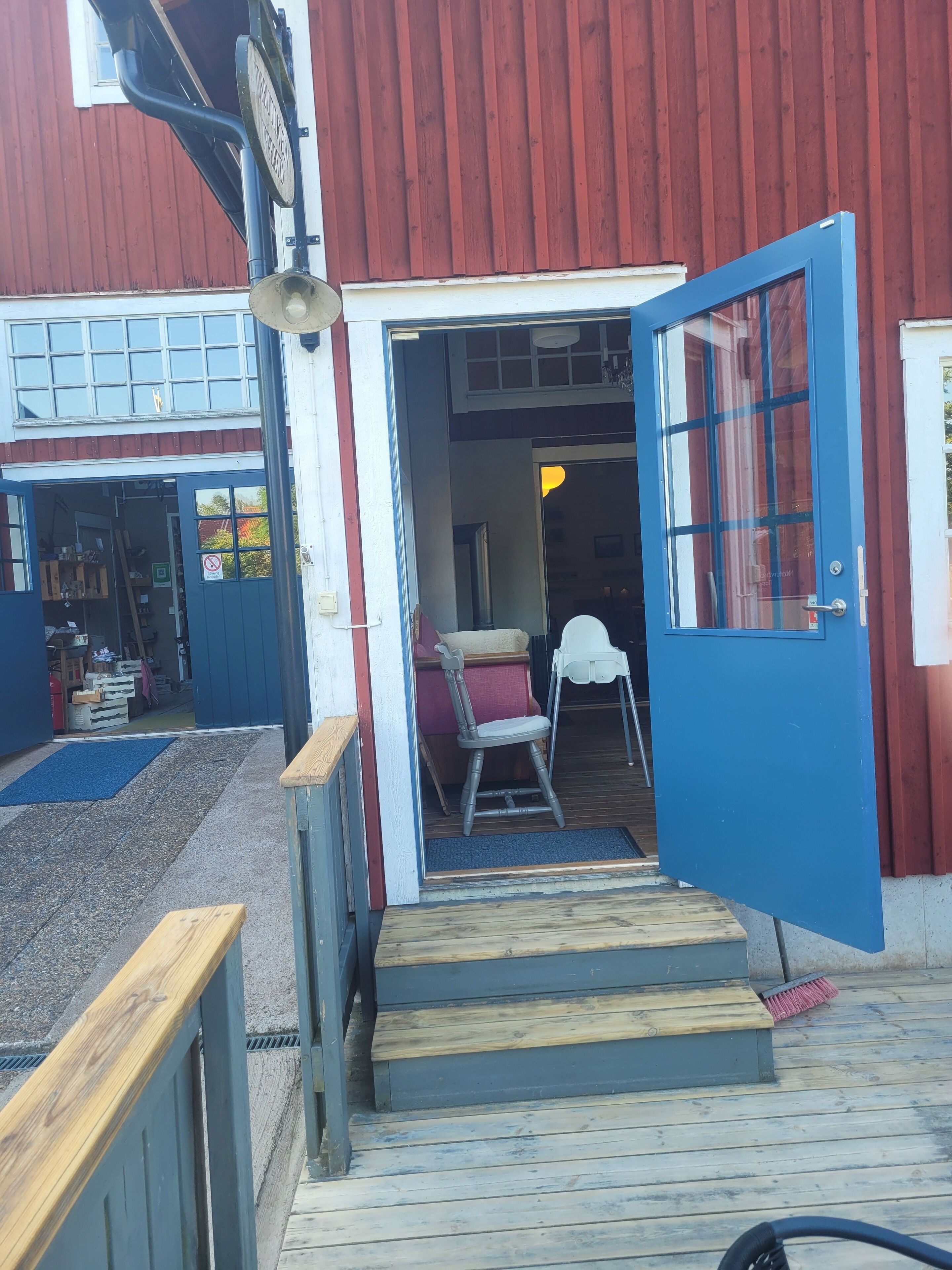 A wooden deck with a blue door leading to a room with a chair and a small table.