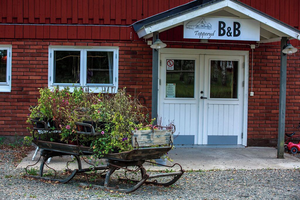 En rød murbygning med en hvid dør og et skilt, der står 'B&B Topperyd'.