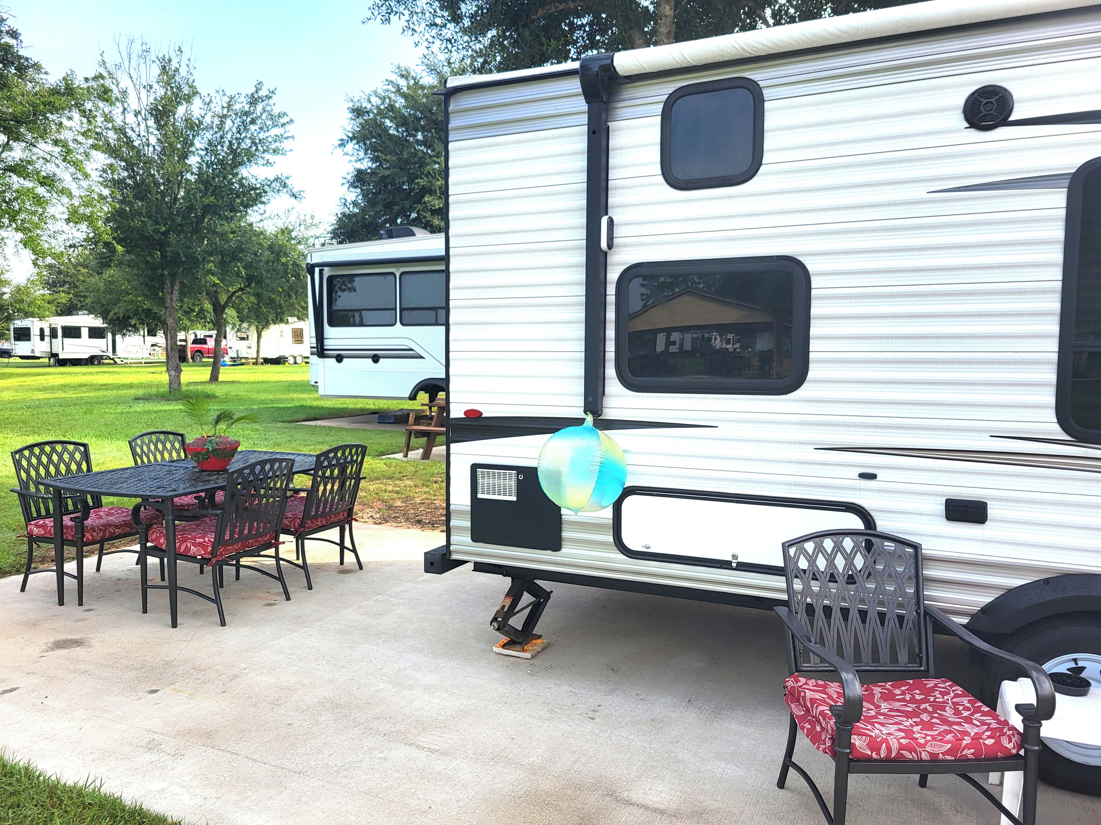A recreational vehicle with a dining area featuring a table and chairs, a small window, and a decorative balloon.