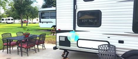 A recreational vehicle with a dining area featuring a table and chairs, a small window, and a decorative balloon.