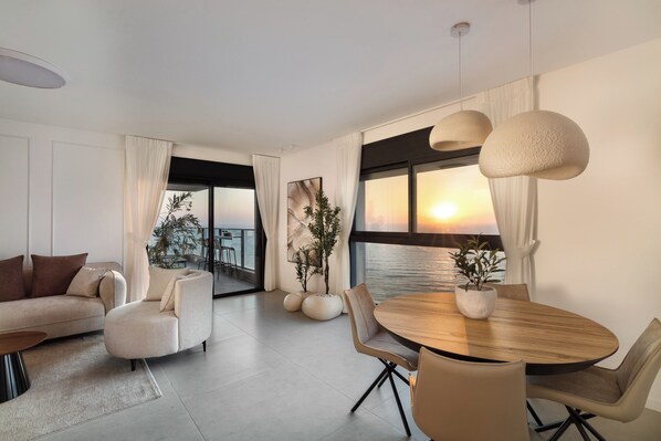 A modern living room with a sofa, armchairs, a dining table, and potted plants.