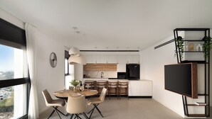 A modern kitchen with white cabinets, a black refrigerator, and a wooden countertop.