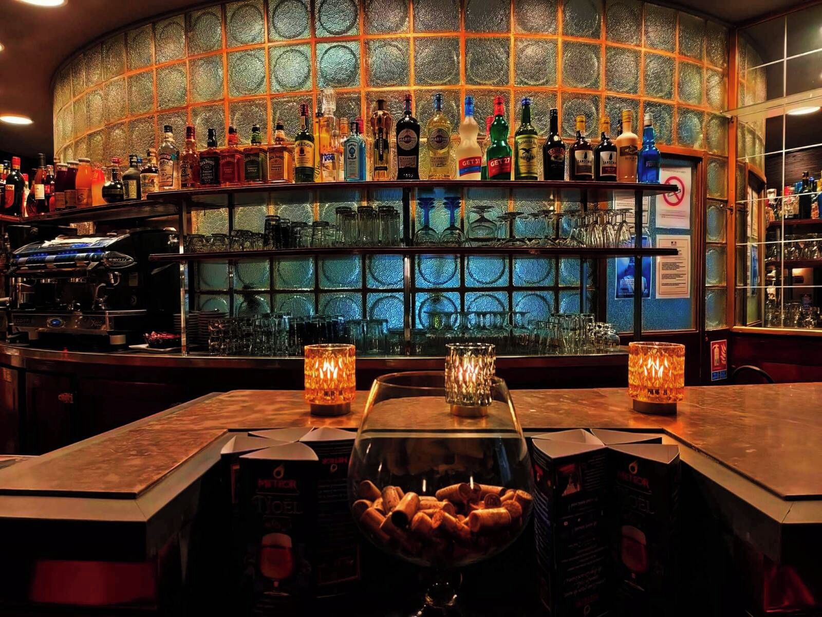 Eine Bar mit einer Glastheke voller Snacks, einer Auswahl an Spirituosenflaschen und einer Kaffeemaschine.