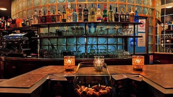 Eine Bar mit einer Glastheke voller Snacks, einer Auswahl an Spirituosenflaschen und einer Kaffeemaschine.