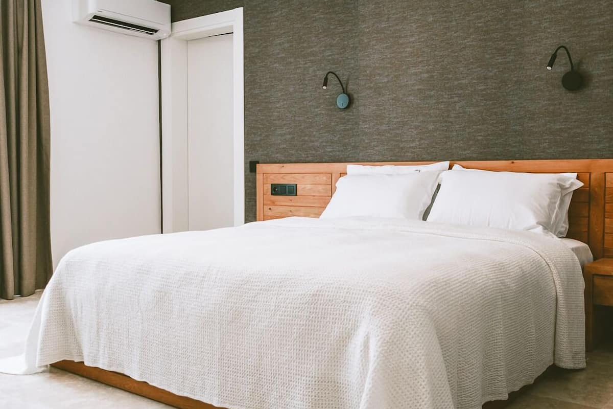 A neatly made bed with a white bedspread in a hotel room.