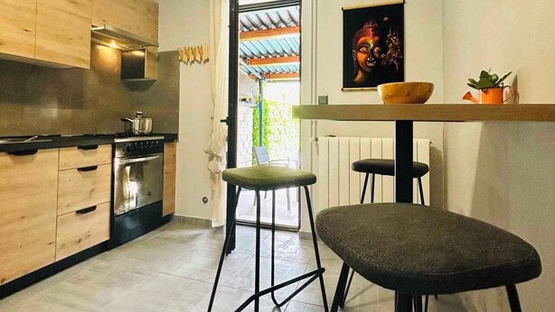 A modern kitchen with wooden cabinets, a built-in oven, and a dining area with stools and a table. - Holiday home with air conditioning and pool (Valbandon)