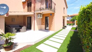 A two-story building with a balcony, outdoor seating area, and a well-maintained lawn. - Holiday home with air conditioning and pool (Valbandon)