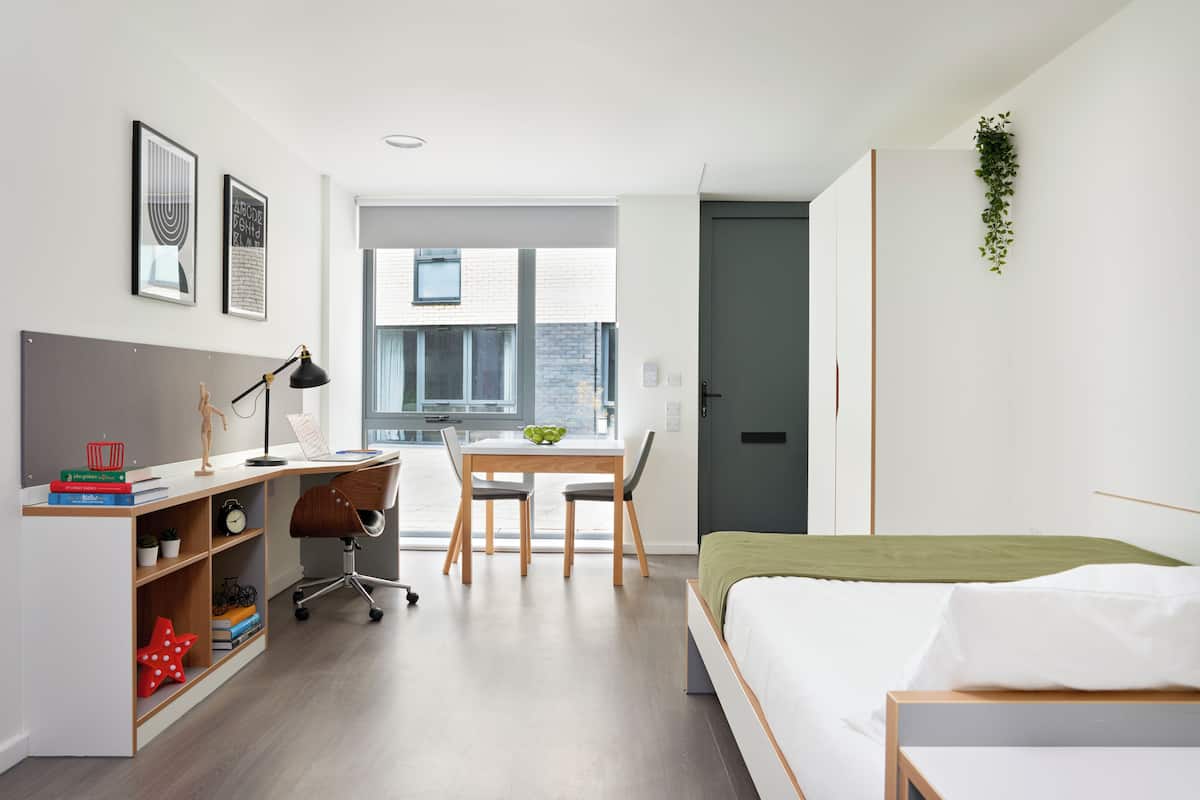 Quarto moderno com cama, escrivaninha, cadeira e estante.