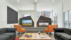 A modern office space with two sofas, a wooden table, and a large window with city views.