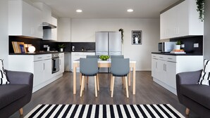 A modern kitchen with white cabinets, a central island, and a dining area with two chairs.